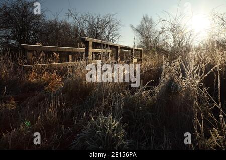 Kleine hölzerne Fußgängerbrücke über landwirtschaftlichen Entwässerungsgraben nördlich von Kirton in Lindsey, North Lincolnshire, Großbritannien. Stockfoto