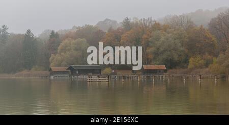 Eching, Deutschland - 6. Nov 2020: Blick auf Bootshäuser am Ammersee. Idyllische bayerische Landschaft an einem nebligen Herbsttag. Stockfoto