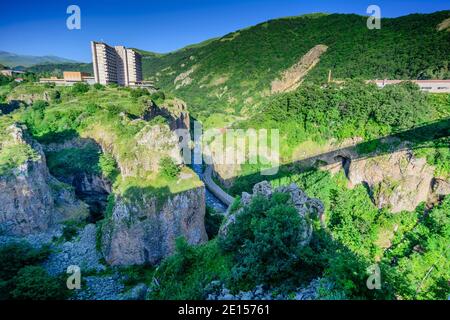Dramatische grüne Bergschlucht mit steilen felsigen Klippen, dichter Vegetation und einer schmalen Straße, die unter einem klaren blauen Himmel durch den Canyon führt, mit bui Stockfoto
