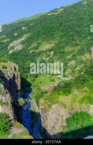 Der Fluss fließt durch eine steile grüne Bergschlucht mit Klippen und dichter Vegetation Stockfoto