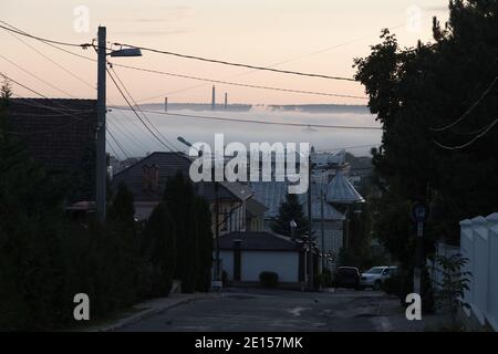 Landschaft einer Stadt am Morgen. Der zentrale Teil der Stadt, darunter, ist mit Nebel bedeckt. Stockfoto