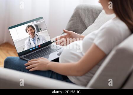 Telemedizin. Unkenntlich schwangere Dame mit Online-Beratung mit Arzt auf Laptop-Computer Stockfoto