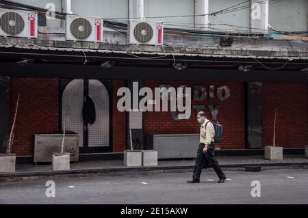 Ein Mann mit einer Maske als vorbeugende Maßnahme gegen die Ausbreitung von covid-19 geht vorbei an einem geschlossenen Nachtclub in Patpong Street.Thailand Regierung ordnete die Schließung von Bars und andere Unterhaltungseinrichtungen und mehrere andere überfüllte Veranstaltungsorte in Bangkok ab 1. Januar 2020 bis 28. Januar 2020 inmitten einer Neue Welle des Coronavirus-Ausbruchs in Thailand. Stockfoto