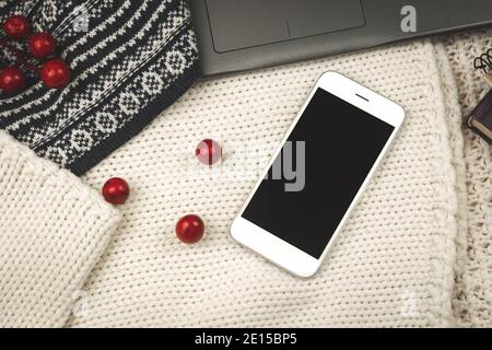 Strickpullover, schwarzes Smartphone und kuschelige Komposition, Arbeitsplatz nach Selbstisolation, Foto Stockfoto