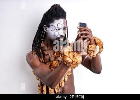 Schockiert einheimischen afrikanischen Mann studieren Handy, mit ihm zum ersten Mal, isoliert auf weißem Hintergrund Stockfoto