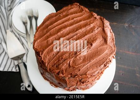Chocolate Stout Cake with Chocolate Bourbon Sour Cream Frosting: Ein ungeschnittener Schokoladenkuchen mit drei Schichten Stockfoto