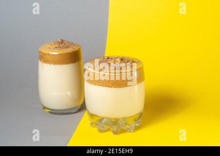 Zwei Gläser Dalgon-Kaffee mit üppigem Schaum auf grau-gelbem Hintergrund, trendigen koreanischen Getränk. Stockfoto