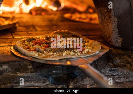 Nahaufnahme der Pizza geht in den Holzofen, kurze Schärfentiefe Stockfoto