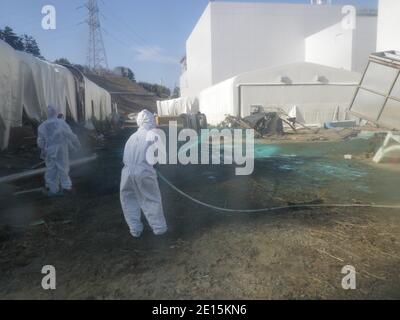 Datei-Foto, aufgenommen am 1. April 2011. Arbeiter, die Schutzanzüge tragen, sprühen im Kernkraftwerk Fukushima Daiichi in der Präfektur Fukushima (Japan) von Tokyo Electric Power Co. (TEPCO) Kunstharz mit Klebstoff über den Boden. Das Drama im Reaktorkomplex Fukushima Daiichi mit sechs Reaktoren hat sich in eine vierte Woche hingezogen, die die globale Atomindustrie beunruhigend und Japans Leiden nach einem Erdbeben und Tsunami, bei dem etwa 27,500 Menschen ums Leben gekommen oder vermisst wurden, noch verschärft. Strahlung ist ins Meer, in Lebensmittel, Trinkwasser und in die Luft gesickert. Es behindert Bemühungen, Überhitzung Brennstäbe kühlen Arbeit in der Anlage Stockfoto