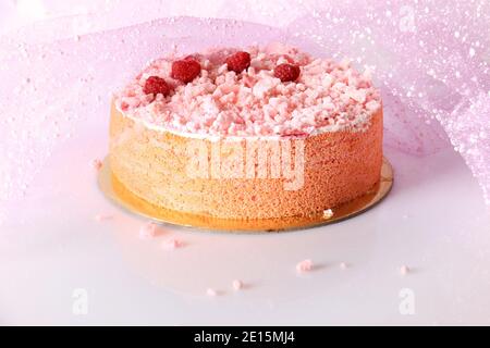 Ein rosa Kuchen mit Baiser bröckelt, Himbeeren, und zuckerhaltigen Rosenblätter. Stockfoto