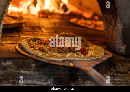 Nahaufnahme der Pizza geht in den Holzofen, kurze Schärfentiefe Stockfoto