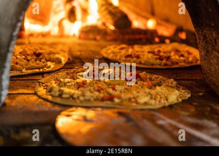 Nahaufnahme der Pizza geht in den Holzofen, kurze Schärfentiefe Stockfoto