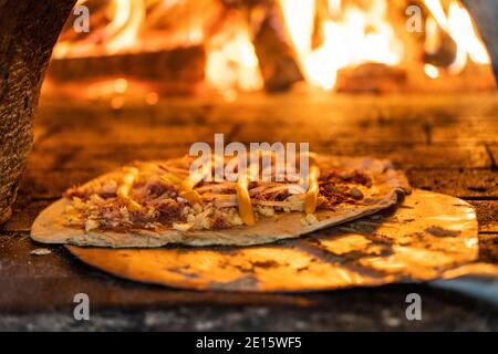 Nahaufnahme der Pizza geht in den Holzofen, kurze Schärfentiefe Stockfoto