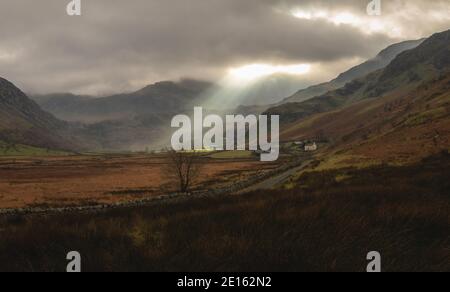 Sonnenstrahlen durchdringen die Wolken und leuchten über den Glyderau-Bergen in der Landschaft des Ogwen-Tals in Snowdonia, Nordwales, Großbritannien. Stockfoto