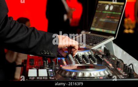 Discjockey in elegantem Anzug mischt Musik auf Party, Nahaufnahme Stockfoto