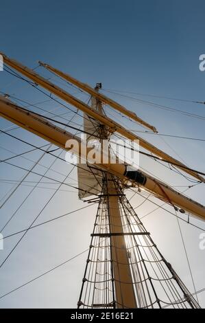 Blick auf Holzmast mit Seilen und Takelage aus Ein altes Segelschiff gegen einen blauen Himmel Stockfoto