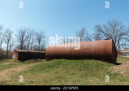 Zwei alte verlassene rostige Fässer liegen im Freien auf dem Gras. Stockfoto