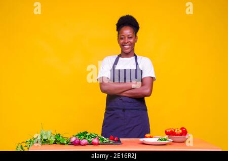 Eine junge afrikanische Dame lächelt, während sie in der Küche steht Stockfoto