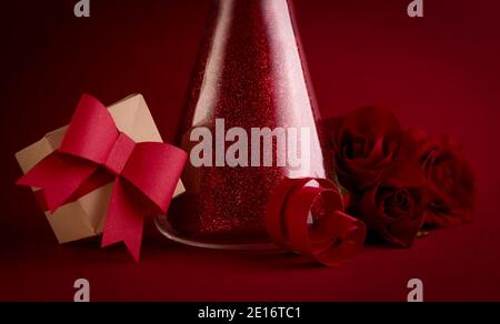 Love Chemistry, Happy Valentines Day Konzept mit funkelndem Trank in Laborglas-Flasche, frischen roten Rosen und Papier-Geschenkbox gegen rote Backgrou Stockfoto