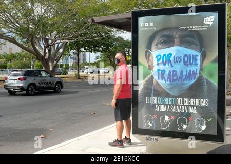 Mann wartet auf den Bus vor einer Werbung, die Menschen ermutigt, Gesichtsmasken während der Pandemie von Covid 19, Merida, Mexiko, zu tragen Stockfoto