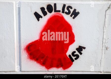 Abschaffen Kapitalismus Graffiti,grafitti,Wandbild,an,Wand,hat,geändert,vandalisiert,zu,abschaffen ISM, ISM,.sieht aus wie ein John Lennon,Lyrik,von Give Peace a Chance...Alle reden über Bagismus, Shagismus, Dragismus, Madism Ragismus, Tagismus, this-ISM, That-ISM, ISM, ISM, ISM. Geballte Faust, verdeckt, entfernt, links, Flügel, Politik. An der Wand im Zentrum von Aberystwyth, Cardigan Bay, Ceredigion.Student, Stadt an der Küste, Küste, Einstellung, West Wales, Wales, Walisisch, Großbritannien,. Stockfoto