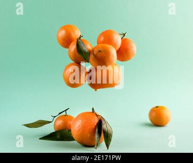 Gruppe von Mandarinen oder Mandarinen mit Blättern schweben auf Ein türkisfarbener Hintergrund Stockfoto