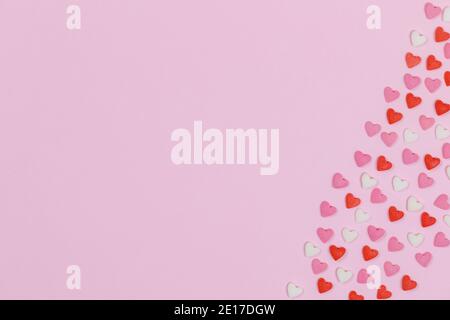Herzförmige Süßigkeiten auf rosa Hintergrund Liebe Hochzeit Konzept verstreut. Valentinstag Muster Hintergrund. Flache Lay-Ansicht von oben. Speicherplatz kopieren Stockfoto