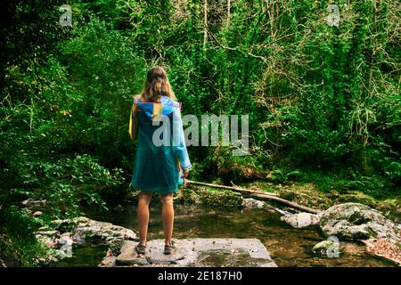 Eine junge Frau steht im Wald bei einem Fluss im Herbst Stockfoto