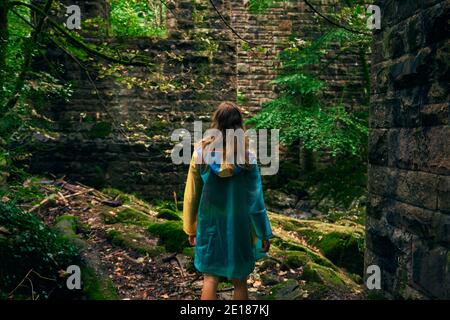 Eine junge Frau geht im Wald an einem vorbei Steinmauer Stockfoto