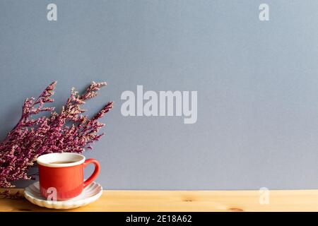 Tasse schwarzen Tee mit rosa nebligen blauen trockenen Blumen auf Holztisch. Grauer Hintergrund Stockfoto