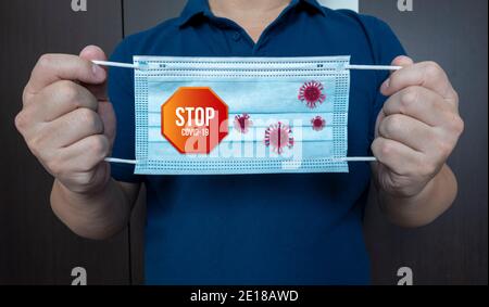 Asiatischer junger Mann mit Schutzmaske und grafischem Wortstopp covid 19. Gegen die Ausbreitung von Coronavirus oder covid-19 Krankheitskonzept. Stockfoto