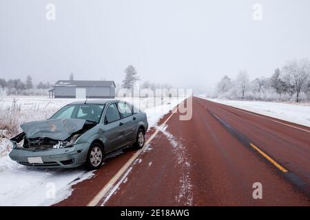 Zertrümmerte Auto und tote Hirsche auf der Seite eines Wisconsin Highway im Winter, horizontal Stockfoto