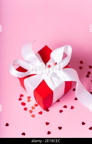Kleine rote Geschenkbox mit weißem Band und Schleife auf rosa Hintergrund. Copyspace. Banner. Das Konzept eines Geschenks für den Tag aller Liebenden oder Muttertag Stockfoto