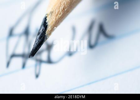 Makrofotografie der Spitze des neu geschärften schwarzen Bleistifts. Hintergrund eines Notizbuchs. Stockfoto