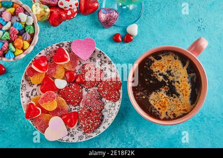 Valentinstag oder romantisches Abendessen mit Süßigkeiten Herzen, eine Tasse heißen Kaffee und elegante Tischeinstellung auf hellblauem Hintergrund Stockfoto