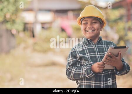 Boy Kid Gelber Helm Schutzhelm Sicherheit Engineering Konzept Holding Tablet Stockfoto