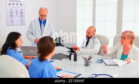 Fachkundiger Arzt im Gespräch über Medizintechnik mit medizinischem Personal im Labormantel. Klinik Experte Therapeut im Gespräch mit Kollegen über Krankheit, medizinische Fachkraft. Stockfoto