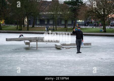 Glasgow, Schottland, Großbritannien. Januar 2021. Im Bild: Ein Einheimischer fotografiert die zerbrochene Skulptur. Queens Park in Shawlands, der heute Morgen nur wenige Menschen im Park und auf dem Eis zeigt, bildet einen deutlichen Kontrast zu den Szenen von gestern, in denen Hunderte von Menschen auf dem Eis, Schlittschuhlaufen, Hockey spielen und um den Park herum zu sehen waren. Ab 00:01 Uhr heute Morgen wurde Schottland erneut gesperrt, wie es die Ansprache des schottischen Ersten Ministers gestern um 14:00 Uhr erklärte. Quelle: Colin Fisher/Alamy Live News. Stockfoto