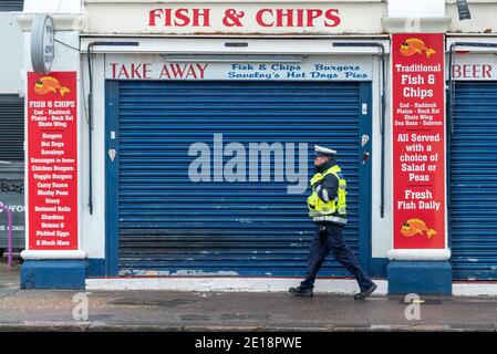 Southend on Sea, Essex, Großbritannien. Januar 2021. Die Küstenstadt Southend on Sea hat zu einem höheren Niveau der COVID 19-Beschränkungen aufgewacht, nachdem Premierminister Boris Johnson England in strengere Tier-5-Sperrbeschränkungen versetzte. Zivilvollstreckungsbeamter patrouilliert am Meer, vorbei an geschlossenen Geschäften. Fish & Chip Shop. Dritte UK-Sperre. Stockfoto