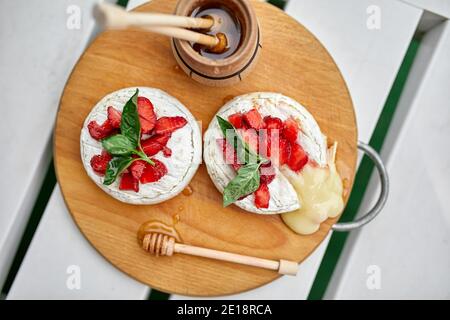 Gegrillter Camembert-Käse mit Erdbeer-, Honig- und Basilikumblättern, Delikatessen, Camembert-Käsefondue auf weißem Hintergrund. Stockfoto