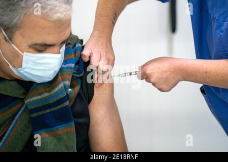 Krankenschwester, die einen Mann mit dem Impfstoff Pfizer-BioNTech Covid 19 impft Stockfoto
