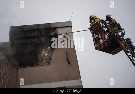 Berlin, Deutschland. Januar 2021. Feuerwehrleute lösen die Verkleidung auf dem Dach eines Hauses. Feuerwehrleute löschten einen Wohnungsbrand im Bezirk Kreuzberg. Quelle: Christophe Gateau/dpa/Alamy Live News Stockfoto