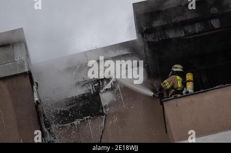 Berlin, Deutschland. Januar 2021. Ein Feuerwehrmann löscht die Verkleidung auf dem Dach eines Hauses. Feuerwehrleute löschten einen Wohnungsbrand im Bezirk Kreuzberg. Quelle: Christophe Gateau/dpa/Alamy Live News Stockfoto