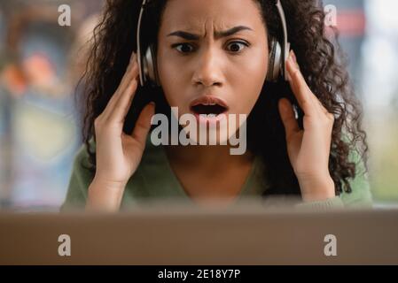 Schockiert afroamerikanische Frau hören Podcast im Café Stockfoto