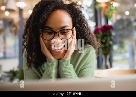 Erstaunt afroamerikanische Frau in Gläsern berühren Wangen Stockfoto