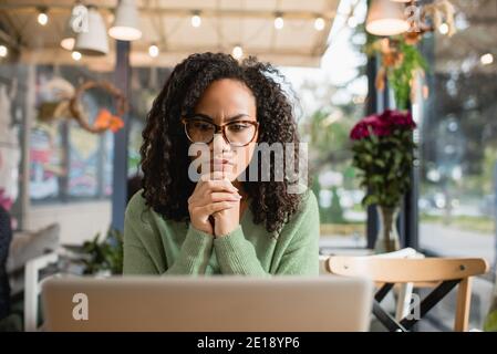 Nachdenkliche afroamerikanische Frau mit geballten Händen Blick auf Laptop Stockfoto