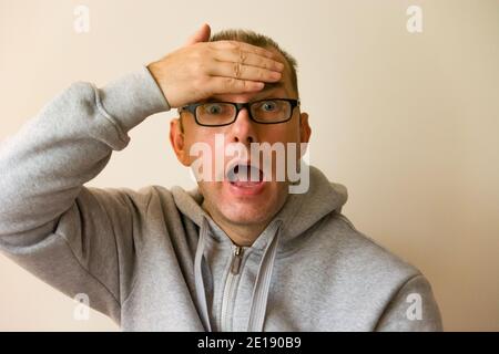 Überraschender Mann, der sich an seiner Stirn hielt Stockfoto