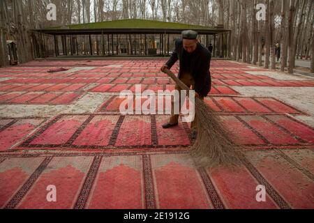 Kashgar, China. 18. März 2016 Uiguren Mann entfernt Blätter von Gebetsteppichen in ID Kah Moschee nach dem Morgengebet in der Altstadt von Kashgar Stadt, in der weit westlichen Xinjiang Provinz, China Stockfoto