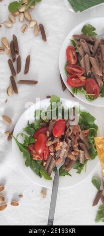 Buchweizen braune Pasta in weißen Schalen mit Tomaten, geräuchertem Lachs und Raketen Stockfoto