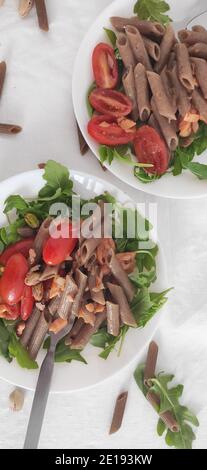 Buchweizen braune Pasta in weißen Schalen mit Tomaten, geräuchertem Lachs und Raketen Stockfoto